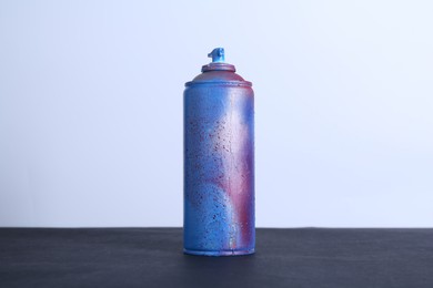 Spray paint can on black surface against white background