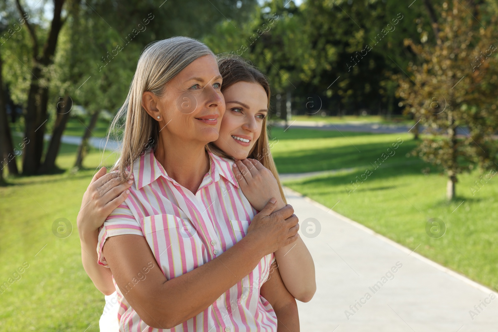 Photo of Family portrait of happy mother and daughter spending time together in park. Space for text