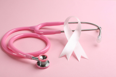 Pink ribbon and stethoscope on color background, closeup. Breast cancer concept