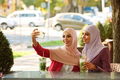 Photo of Muslim women taking selfie in outdoor cafe