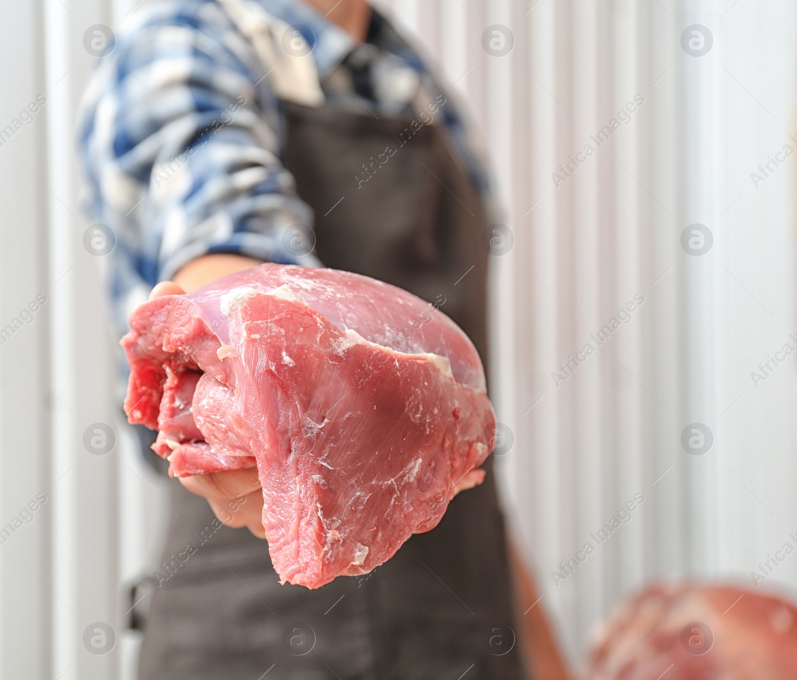 Photo of Male butcher holding fresh raw meat in shop, closeup