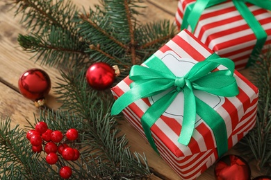 Christmas gift boxes with green bows and fir branches on wooden table, closeup