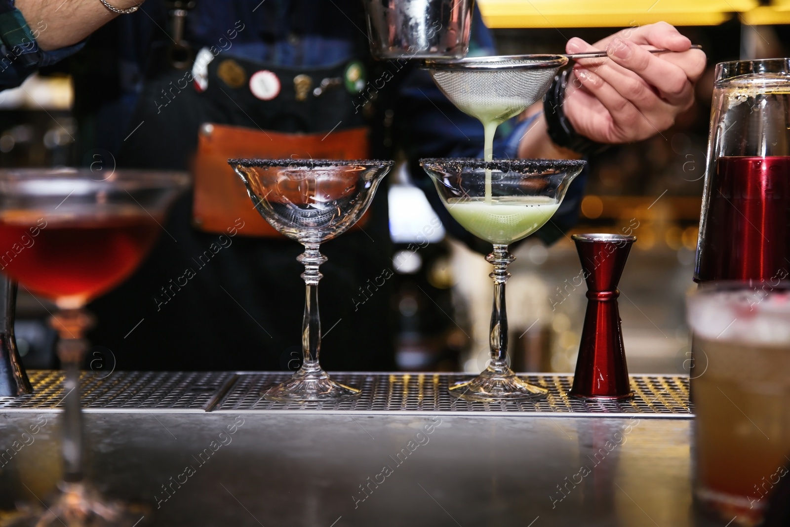 Photo of Bartender pouring tasty cocktail at counter in nightclub, closeup