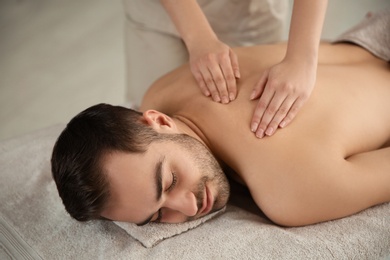 Photo of Handsome man receiving back massage in spa salon