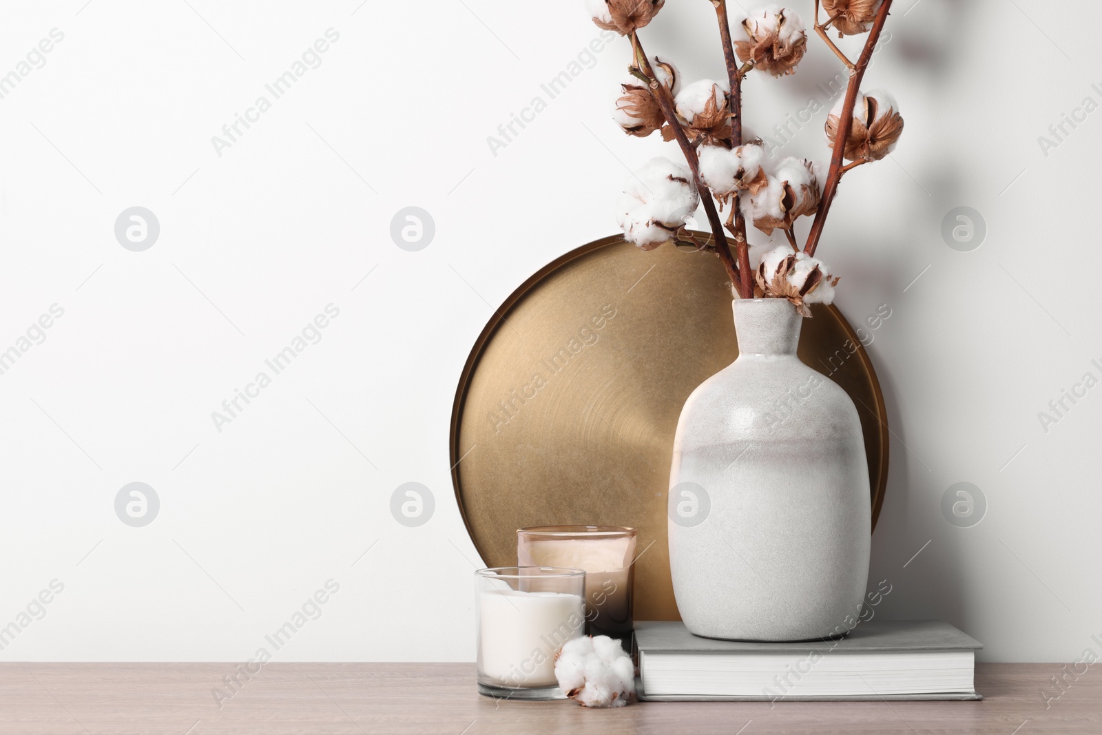 Photo of Candles, book and vase with cotton branches on wooden table against white background. Space for text