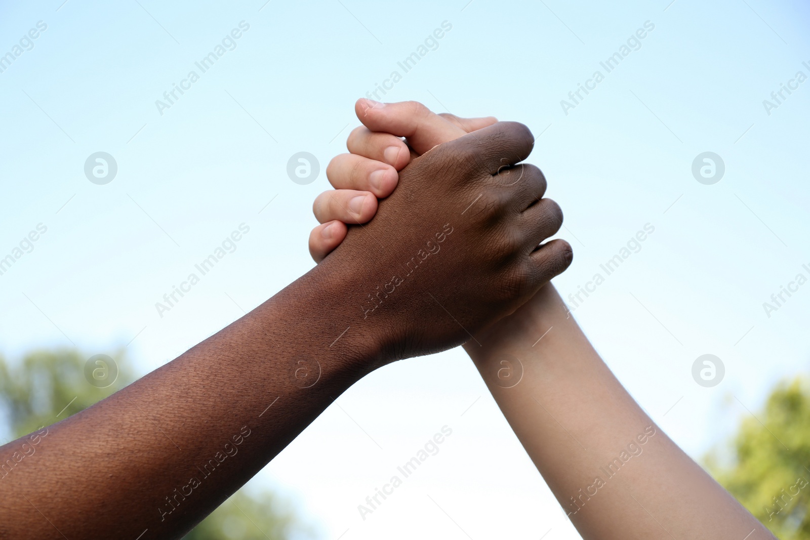 Photo of Closeup view of men clasping hands outdoors