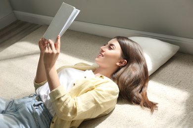 Beautiful young woman reading book at home