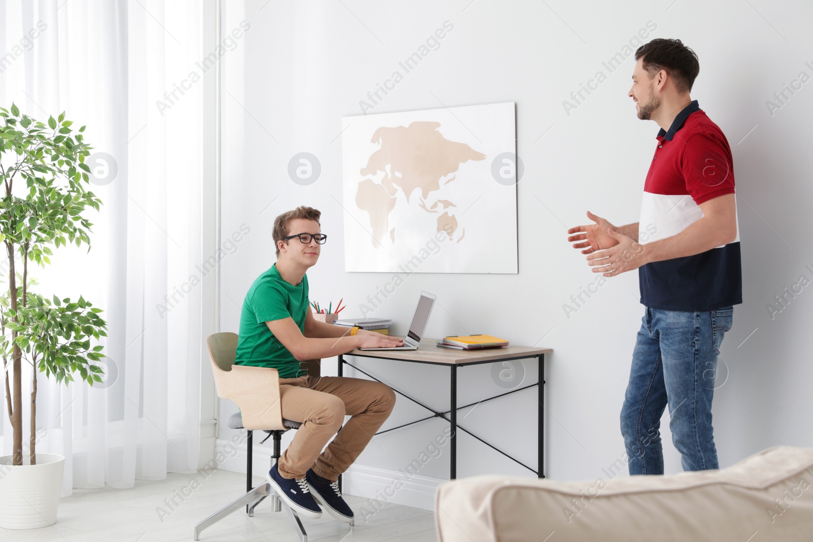 Photo of Father talking with his teenager son at home