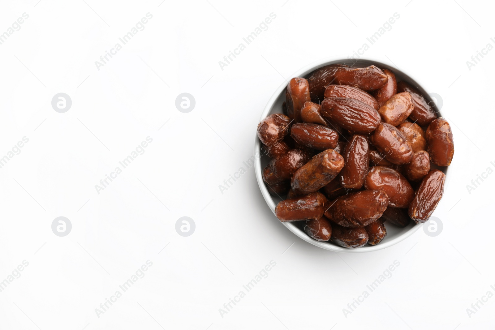 Photo of Bowl with sweet dried date fruits on white background, top view. Space for text