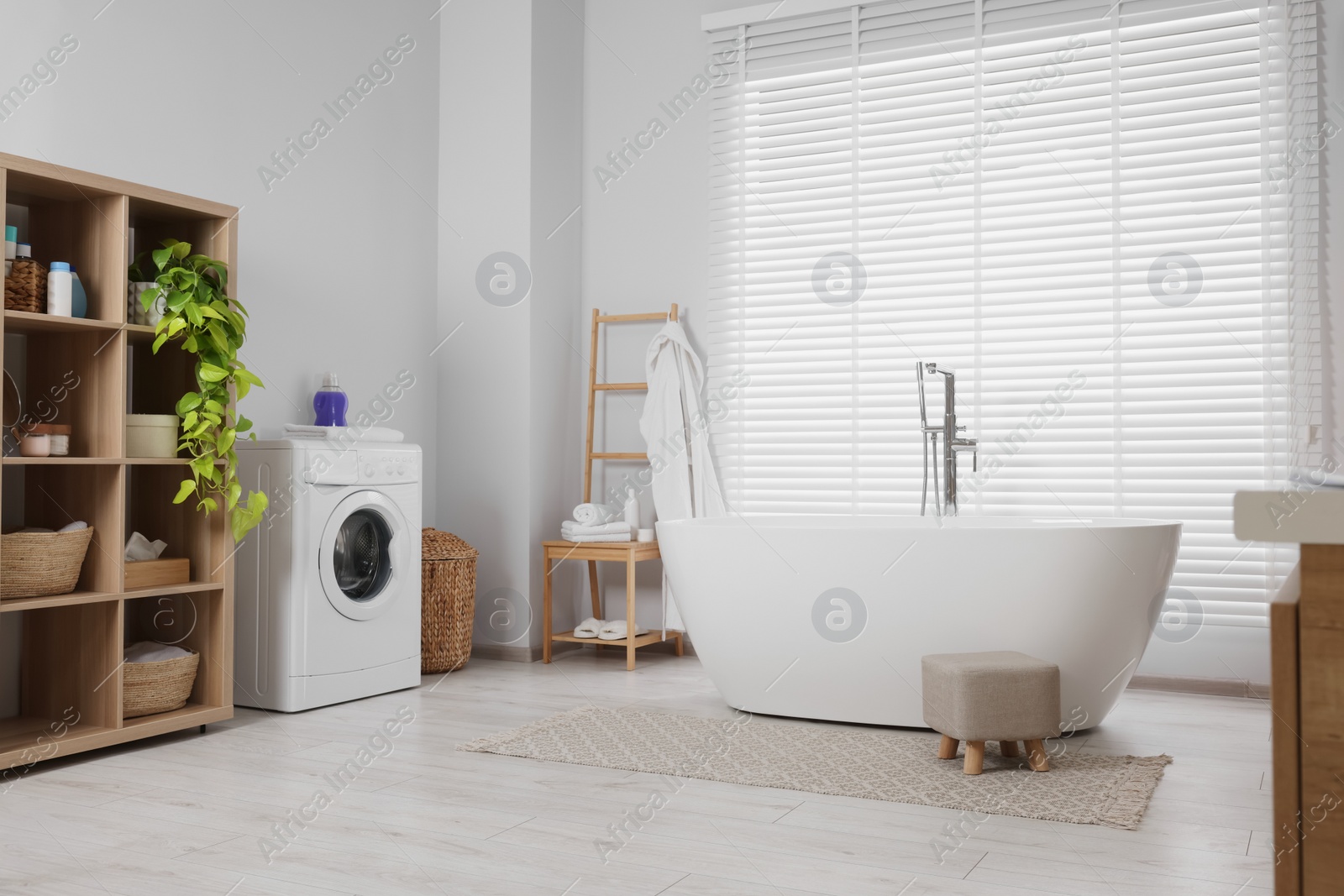 Photo of Stylish bathroom interior with beautiful tub, washing machine and decor elements