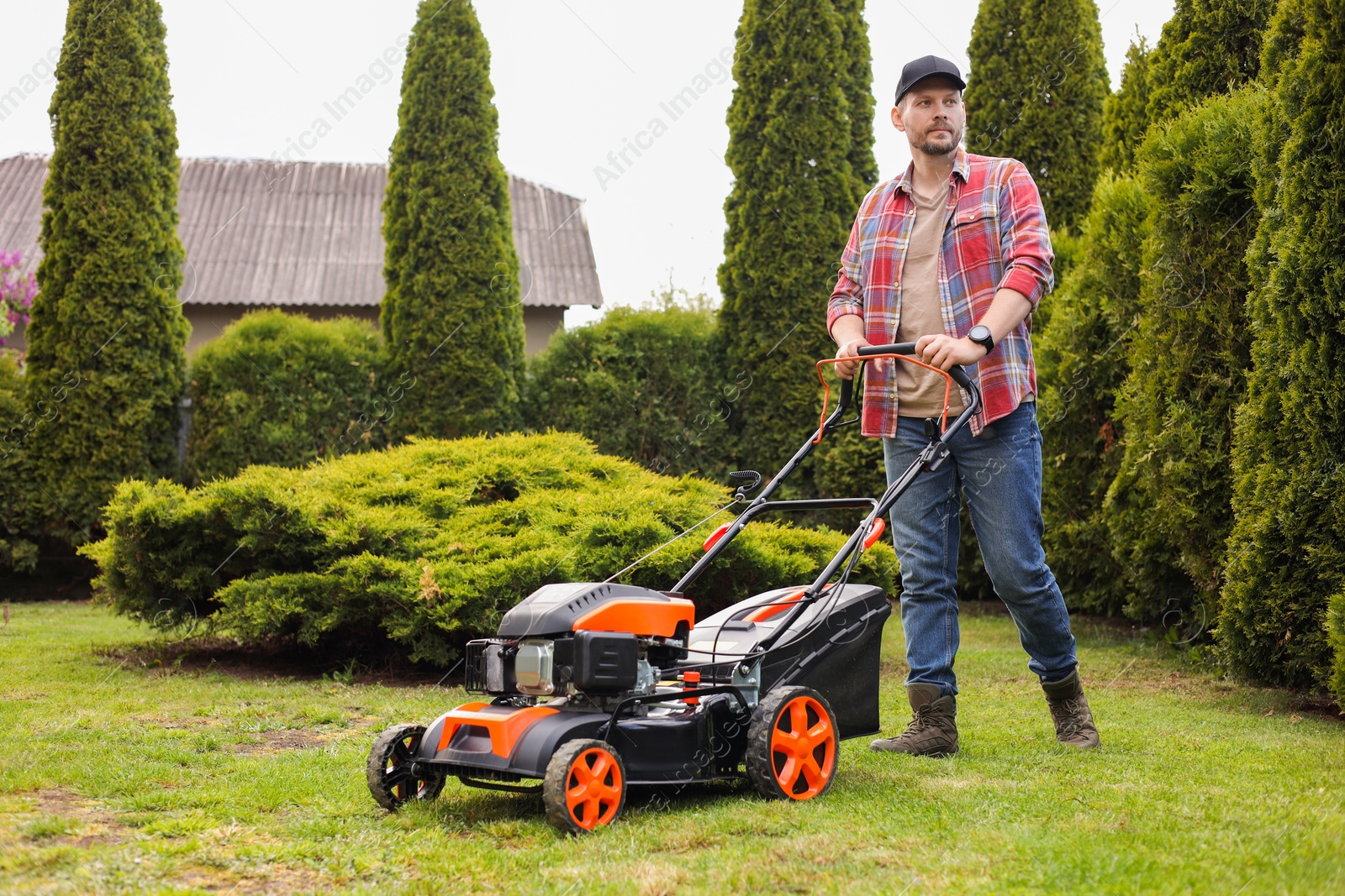 Photo of Man cutting green grass with lawn mower in garden