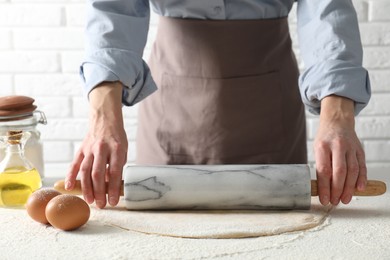 Photo of Woman rolling raw dough at table, closeup