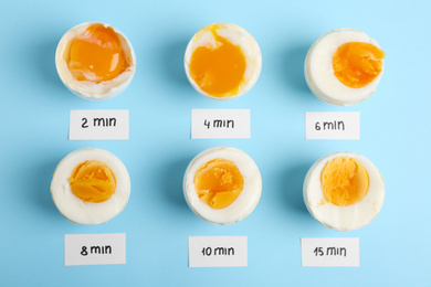 Photo of Different cooking time and readiness stages of boiled chicken eggs on light blue background, flat lay