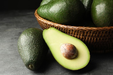 Delicious ripe avocados on grey table against dark background