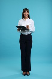 Photo of Happy secretary with clipboard and pen on light blue background