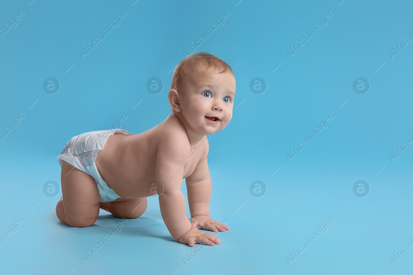 Photo of Cute baby in dry soft diaper crawling on light blue background. Space for text