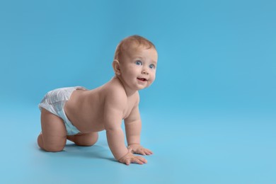 Photo of Cute baby in dry soft diaper crawling on light blue background. Space for text