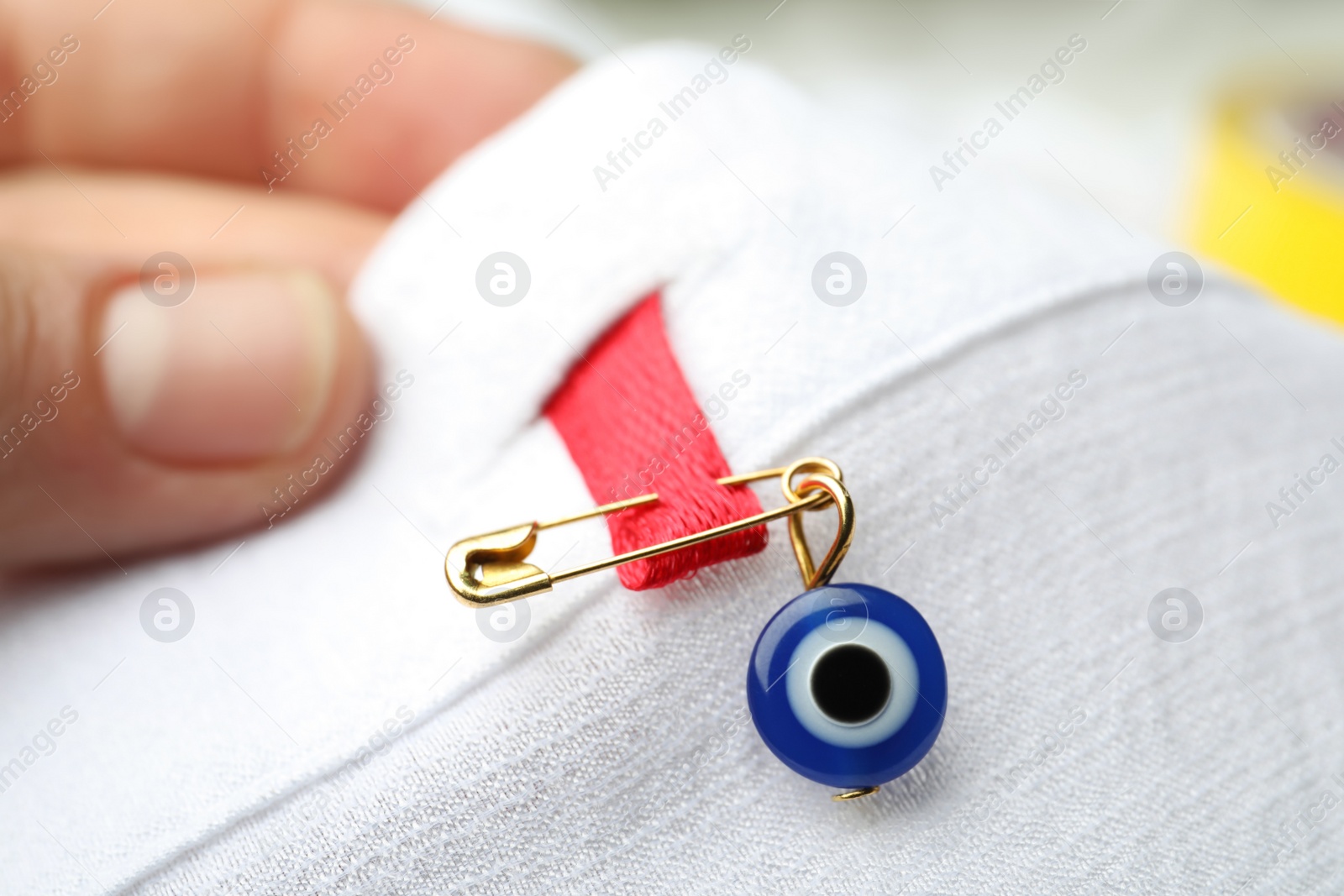 Photo of Woman holding clothing with evil eye safety pin, closeup