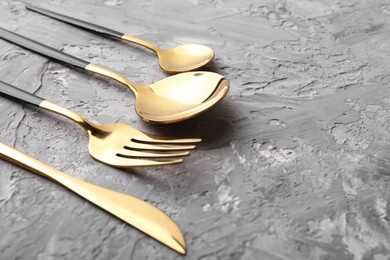 Elegant cutlery set on grey textured table, closeup. Space for text