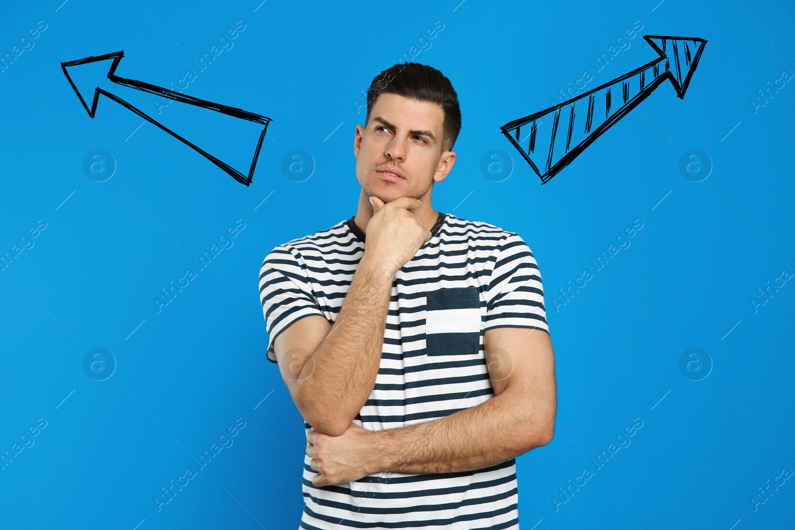 Image of Pensive man standing near blue wall with arrows