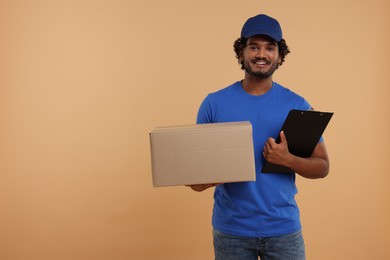 Photo of Happy courier with parcel and clipboard on light brown background, space for text