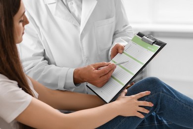 Photo of Doctor showing medical card to patient in clinic, closeup