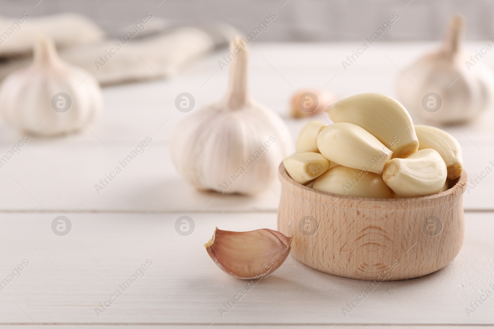 Photo of Fresh garlic on white wooden table, closeup. Space for text