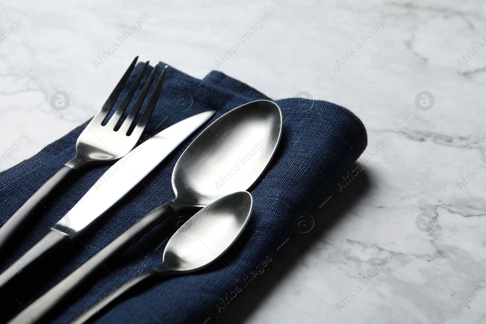 Photo of Stylish cutlery and napkin on white marble table