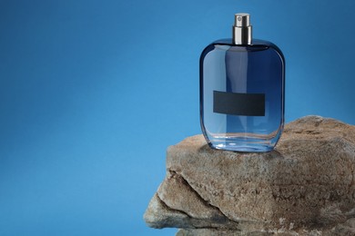 Photo of Stylish presentation of luxury men`s perfume on stone against light blue background. Space for text