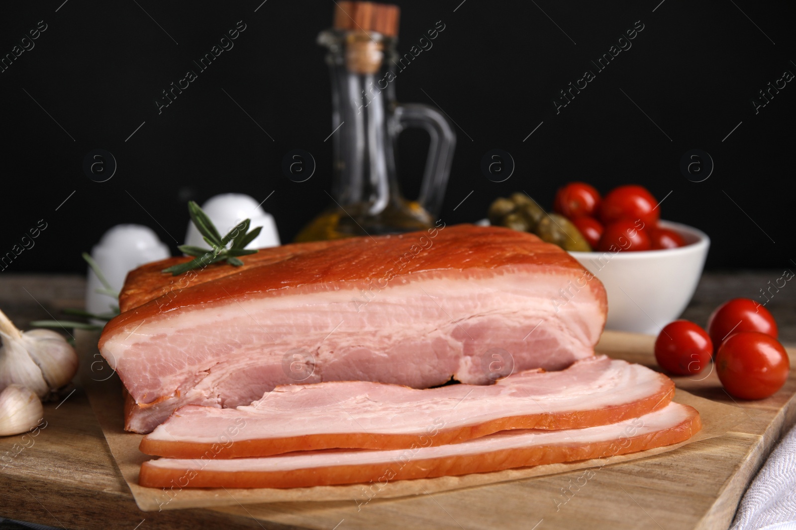 Photo of Delicious smoked bacon with rosemary on wooden board, closeup