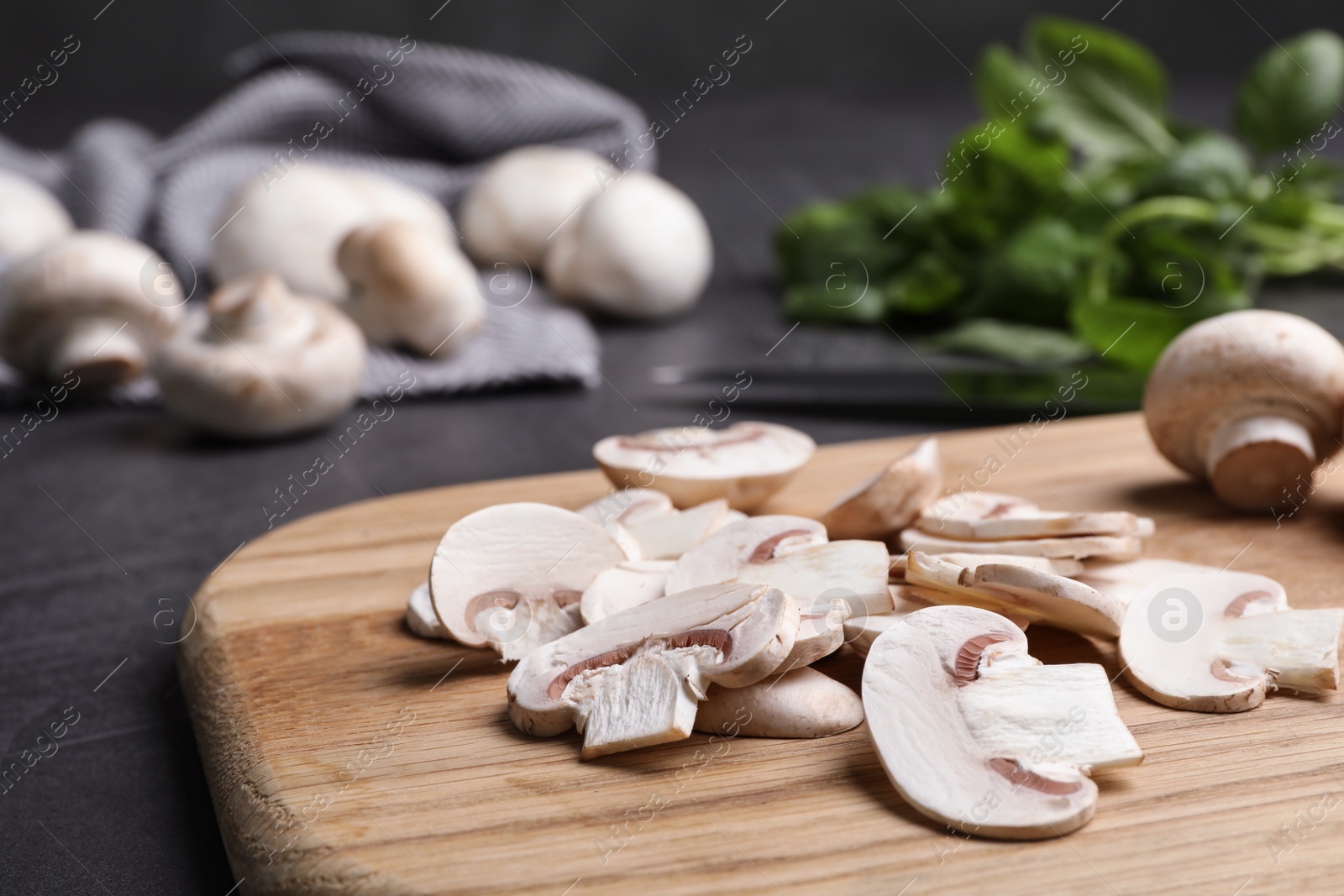 Photo of Wooden board with sliced raw mushrooms on table, closeup