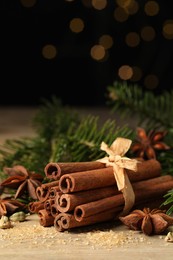 Photo of Different aromatic spices and fir branches on wooden table, space for text