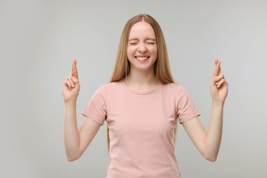 Photo of Woman crossing her fingers on grey background