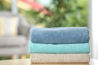 Photo of Stack of folded clean soft towels on table indoors
