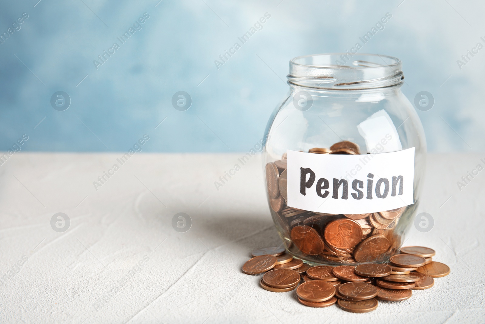 Photo of Glass jar with label PENSION and coins on white table. Space for text