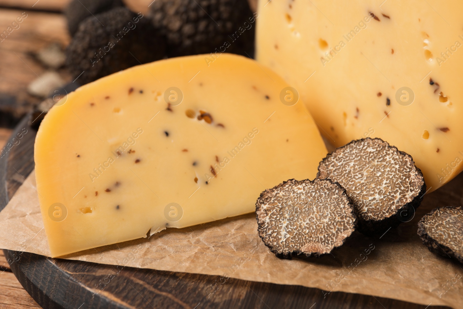 Photo of Delicious cheese with fresh truffles on wooden board, closeup