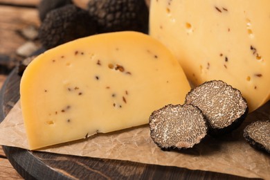 Photo of Delicious cheese with fresh truffles on wooden board, closeup