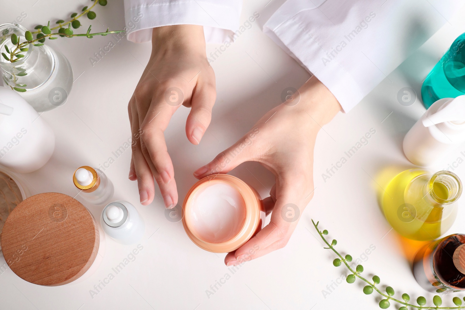 Photo of Dermatologist with jar of cosmetic product at white table, top view. Development and testing