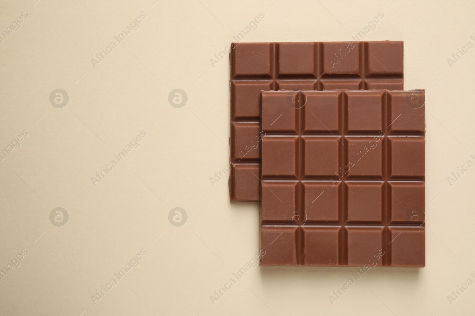 Photo of Delicious chocolate bars on beige background, flat lay. Space for text