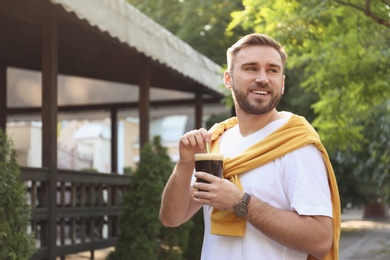 Photo of Handsome man with cold kvass outdoors. Traditional Russian summer drink