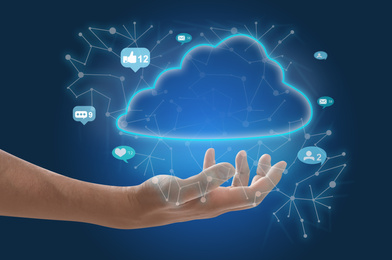 Man demonstrating digital cloud with icons on blue background, closeup. Modern technology