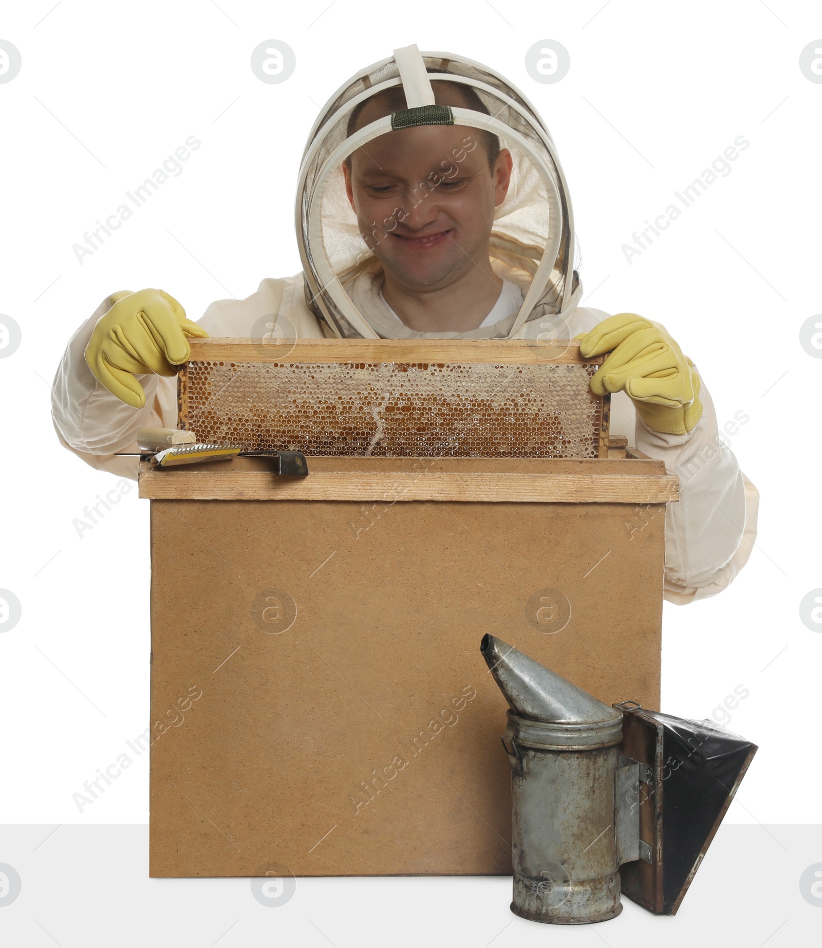 Photo of Beekeeper in uniform taking frame with honeycomb out of wooden hive on white background