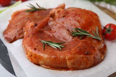 Photo of Raw marinated meat and rosemary on table, closeup