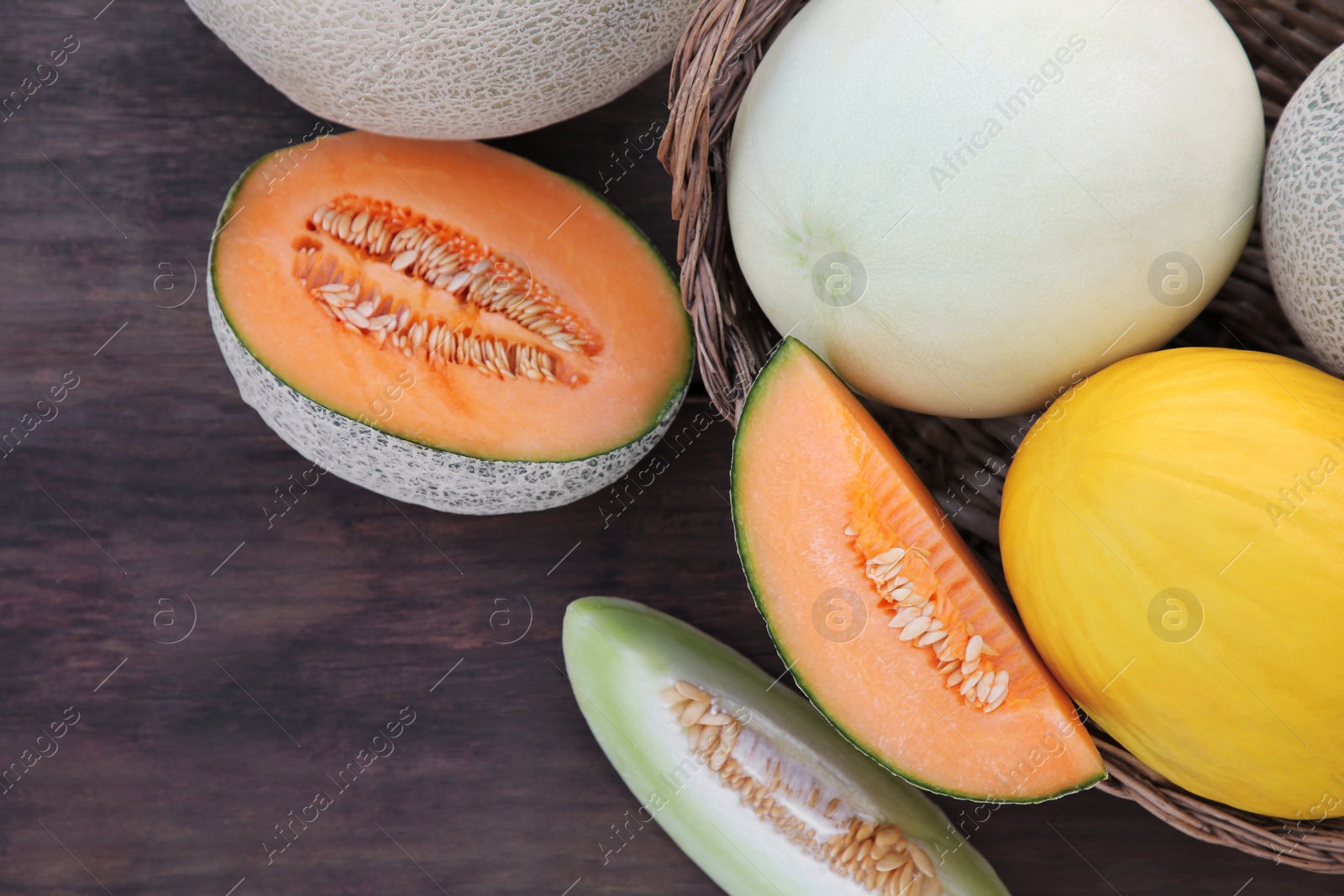 Photo of Tasty ripe melons on wooden table, flat lay