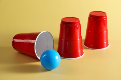 Photo of Shell game. Three red cups and ball on yellow background
