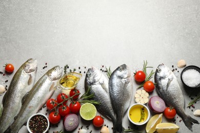 Flat lay composition with dorada and cutthroat fish on light grey table, space for text