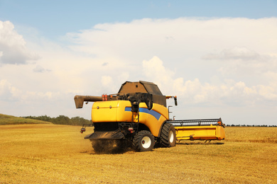 Photo of Modern combine harvester in field on sunny day. Agricultural machinery