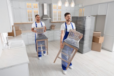 Photo of Male movers carrying chairs in new house