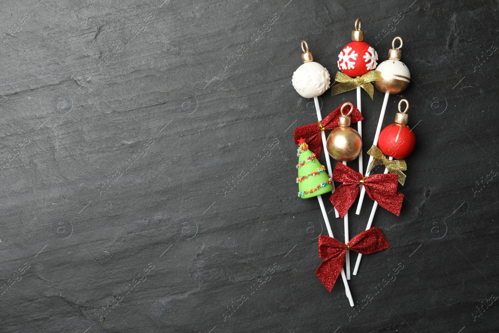 Photo of Delicious Christmas themed cake pops on black table, flat lay. Space for text