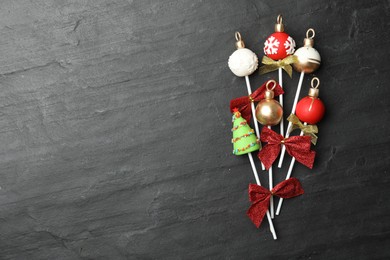 Delicious Christmas themed cake pops on black table, flat lay. Space for text